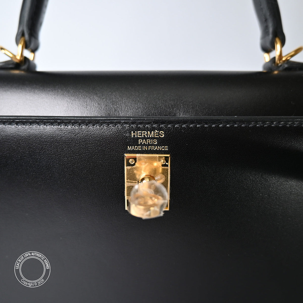 Hermès Kelly 25 in Black Box calfskin leather, close-up of gold turnlock and Hermès Paris stamp