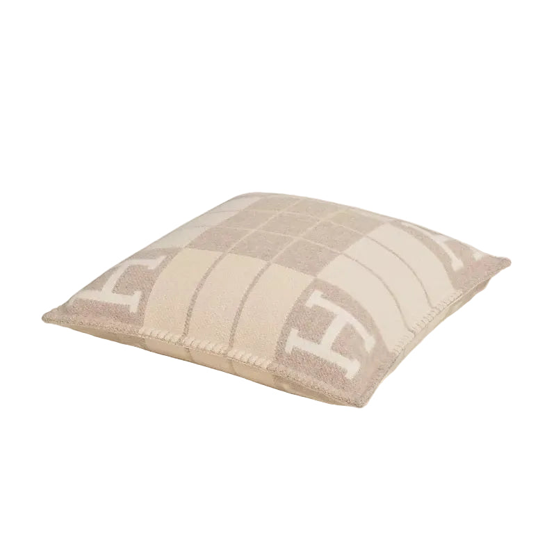 Gray and white checkered pillow with letter 'H' on a beige background