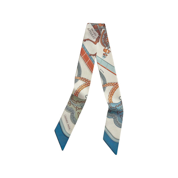 A silk necktie with a detailed nautical print featuring ships, ropes, and waves in blue, orange, and brown on an off-white background, displayed against a light beige wall.