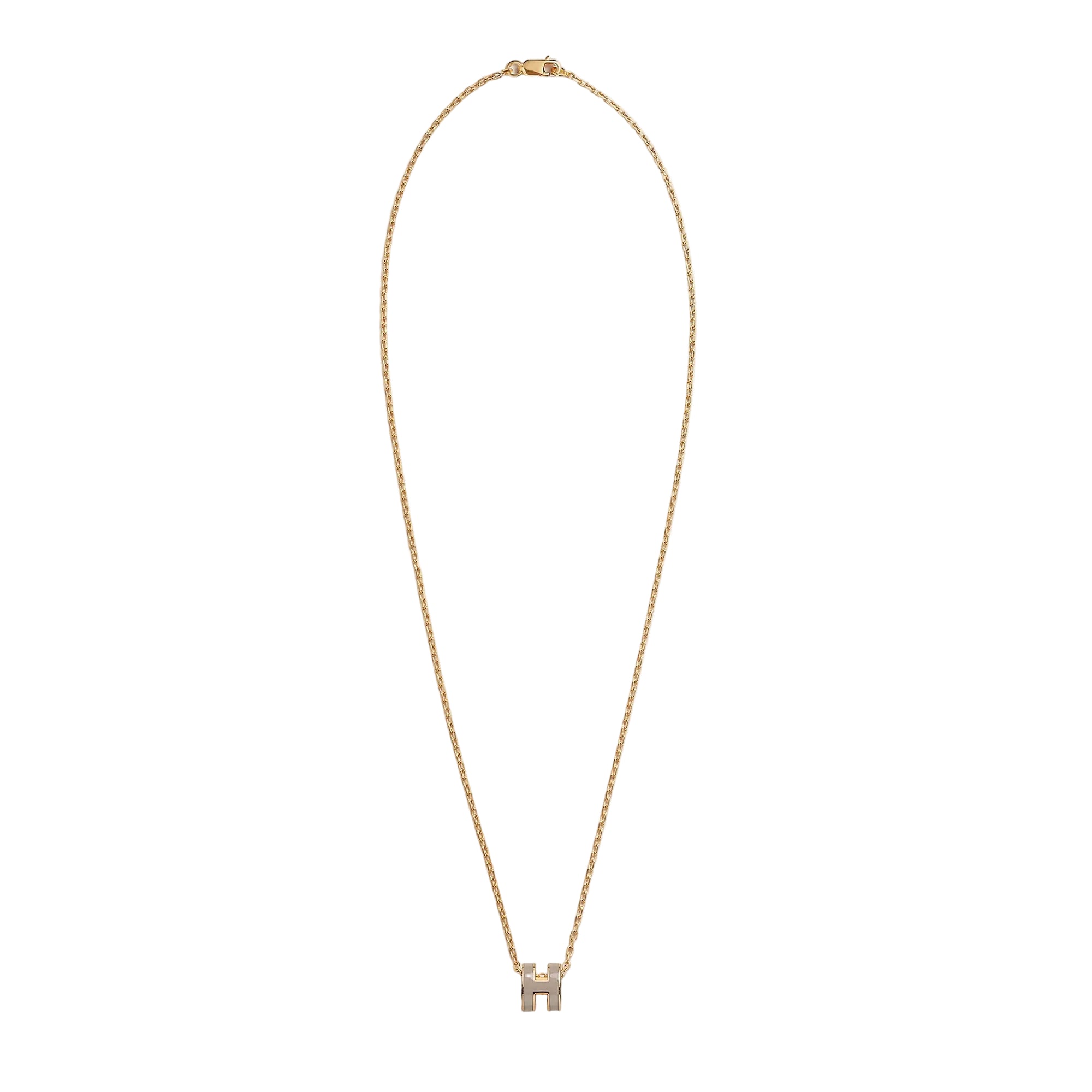 A delicate gold chain necklace with a small bow-shaped pendant set with clear stones, displayed against a solid light beige background.